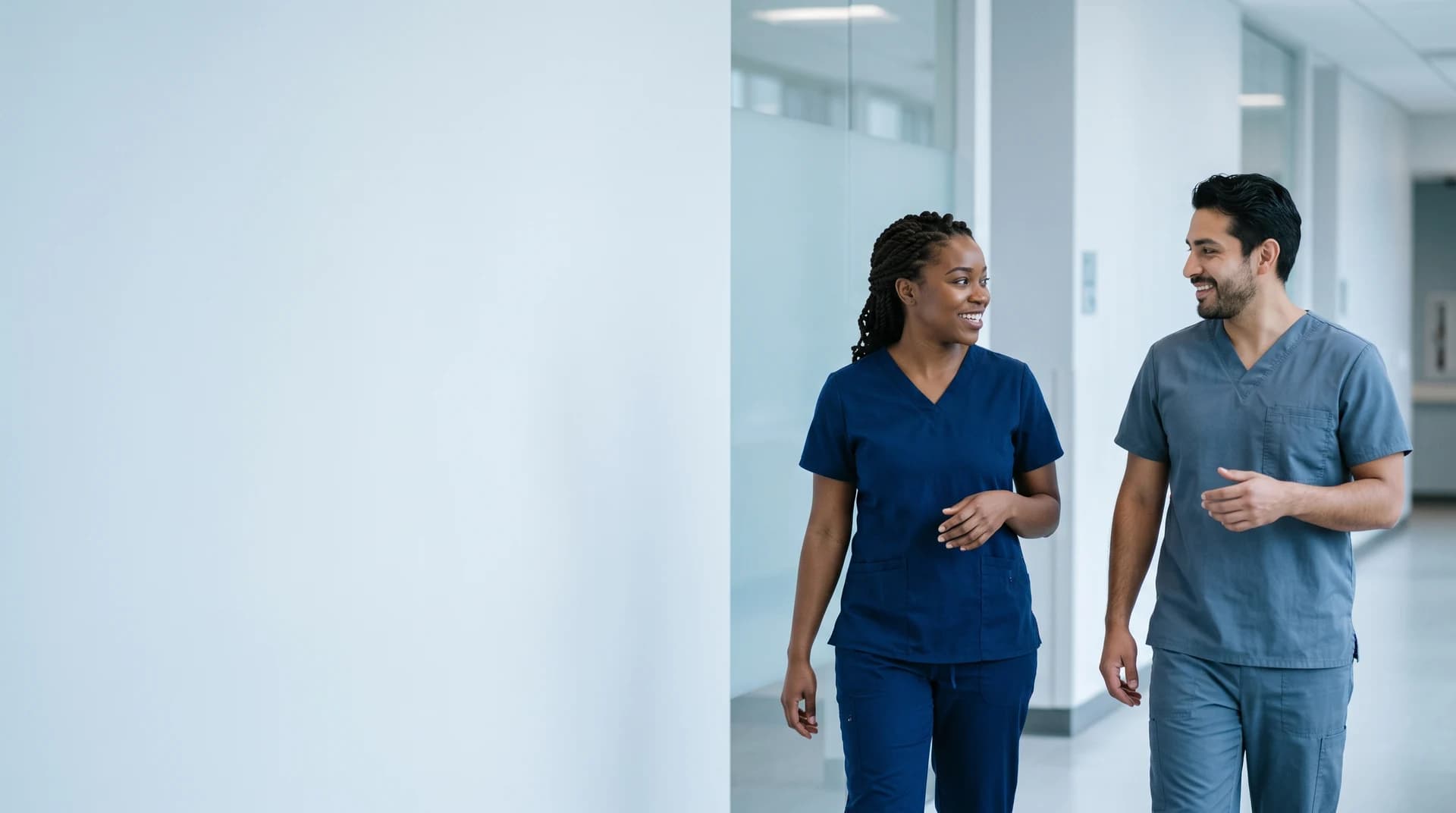 Illustrative scene: two nurses talking as they walk through a hospital corridor.
